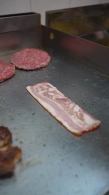 A cook frying the burgers on the griddle in the kitchen of the bar or restaurant