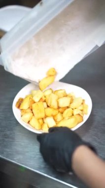 Barın ya da restoranın mutfağındaki fritözde patates kızartması yedikten sonra tepsiye koyan bir aşçı.