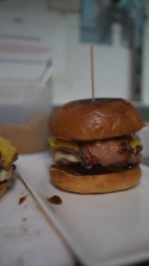 A cook preparing the burger with bacon and cheese in the kitchen of the bar or restaurant