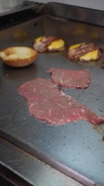 A cook preparing the burger with bacon and cheese in the kitchen of the bar or restaurant