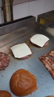 A cook preparing the burger with bacon and cheese in the kitchen of the bar or restaurant