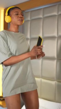 Portrait of rich black ethnic woman walking in hotel room corridor, luxury concept