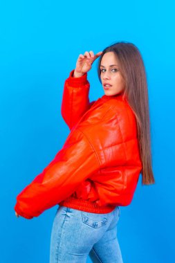 Close up portrait of young caucasian woman in red windbreaker isolated on blue studio background