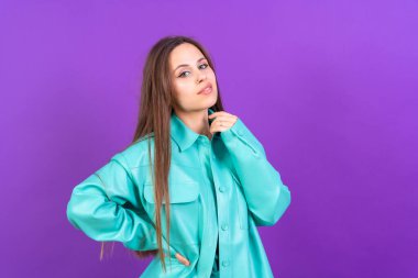 Close up portrait of a young caucasian woman in blue trench coat isolated on purple background, smiling
