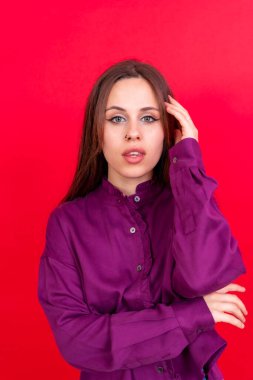 Close up portrait of a young caucasian woman in purple shirt isolated on red background, smiling