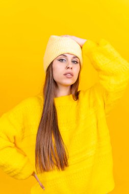 Close up portrait of young caucasian woman in wool sweater isolated on yellow background in studio