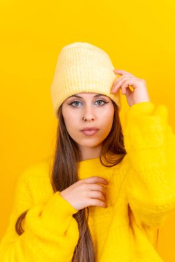 Close up portrait of a young caucasian woman in wool sweater isolated over yellow background, looking at camera