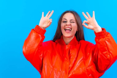 Beautiful woman in casual clothes making ok sign with her hand. successful expression, blue background