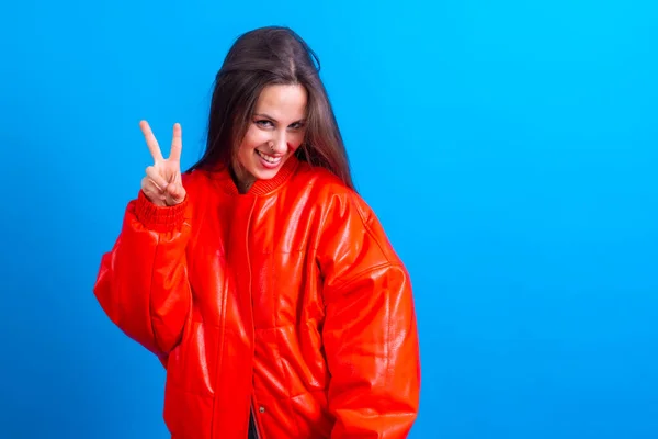 Young woman over blue wall smiling and showing victory sign