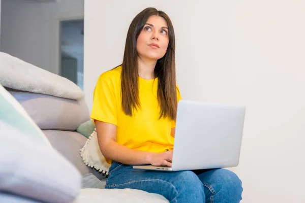 带着电脑坐在沙发上的女人 千禧年的社交网络 沉湎于网上销售 — 图库照片