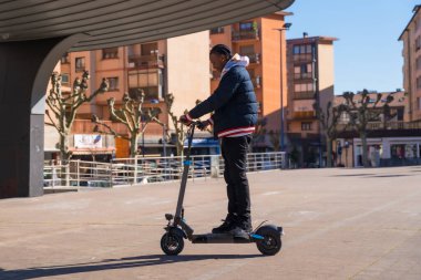 Siyah etnik erkek kaykay, elektrikli kaykay, yeşil ve temiz hareket