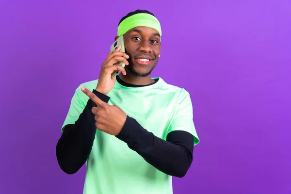 Černý Etnický Muž Telefonem Zelených Šatech Izolovaných Přes Fialové Pozadí — Stock fotografie