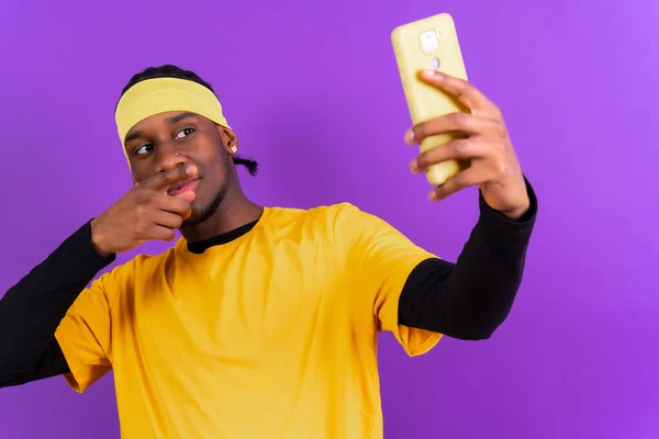 Černoch Telefonem Žlutém Oblečení Fialovém Pozadí Dělá Selfie — Stock fotografie
