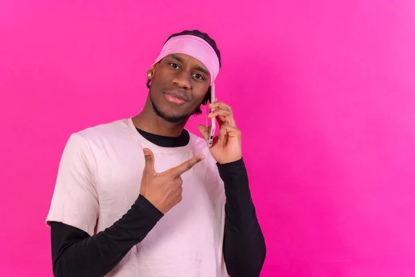 Чёрный Этнический Мужчина Телефоном Розовой Одежде Розовом Фоне Указывающий Телефон — стоковое фото