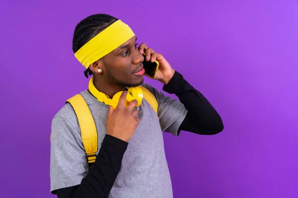 Černoch Batohem Žlutými Sluchátky Fialovém Pozadí Studentský Koncept Telefonování — Stock fotografie