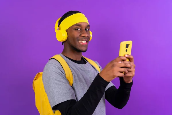 Černý Etnický Muž Batohem Žlutými Sluchátky Fialovém Pozadí Studentský Koncept — Stock fotografie