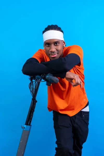 Svart Etnisk Man Orange Kläder Blå Bakgrund Med Elektrisk Skateboard — Stockfoto