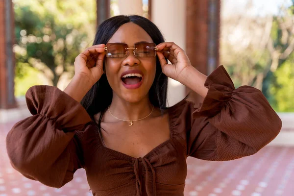 공원을 거닐면서 아름다운 아프리카 여성의 선글라스를 웃으며 — 스톡 사진