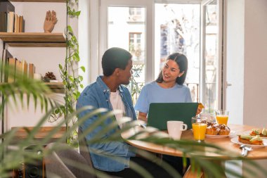 Çift kahvaltı yaparken internetten alışveriş yapıyor, pencerenin yanında, uçuş satın alıyor.