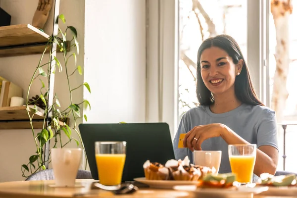 stock image Woman shopping online with computer while having breakfast in the morning by the window with orange juice