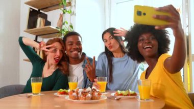 Kahvaltıda, evde portakal suyu ve kek yiyip selfie çeken çok ırklı arkadaşlar.