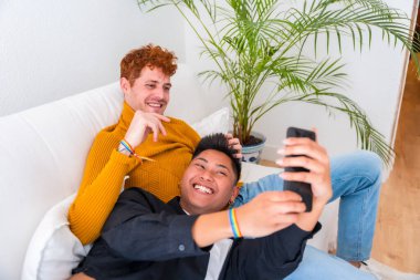 Güzel eşcinsel çift kanepede romantik, eşcinsel çift selfie çekiyor.