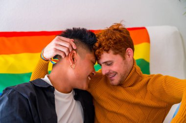 Güzel eşcinsel çift evde kanepede romantik, lgbt konsepti, gökkuşağı bayrağı