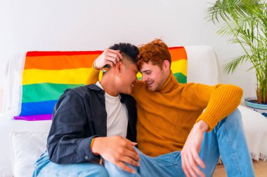 Güzel eşcinsel çift evde kanepede romantik, lgbt konsepti, gökkuşağı bayrağı