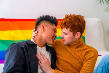Güzel eşcinsel çift evde romantik kanepede öpüşüyor, lgbt konsepti, gökkuşağı bayrağı