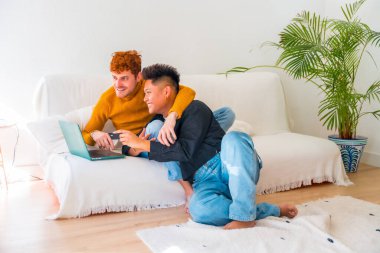 Güzel eşcinsel çift kanepede romantik oluyor kucaklaşıyorlar, Igbt konsepti, online alışveriş yapıyorlar.