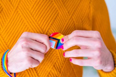 Yakasında lgbt bayrağı olan metal bir rozet.