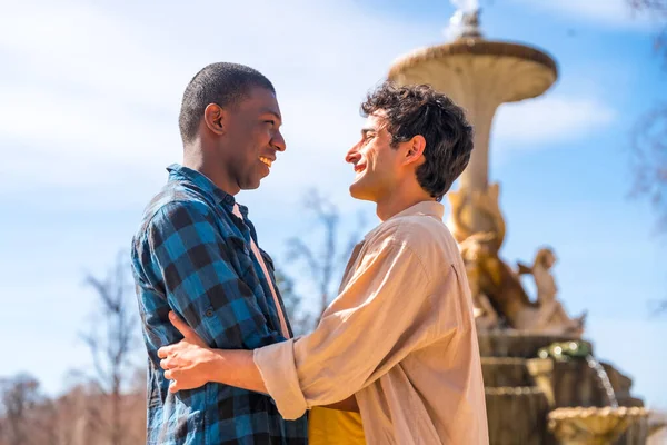 一对多种族的男人在一座城市的喷泉里 依依不舍的观念 摆出浪漫的姿势 彼此微笑着看着对方 — 图库照片