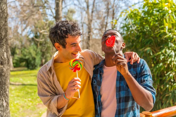 一对多民族男人吃棒棒糖 棒棒糖的概念 有乐趣和微笑 — 图库照片