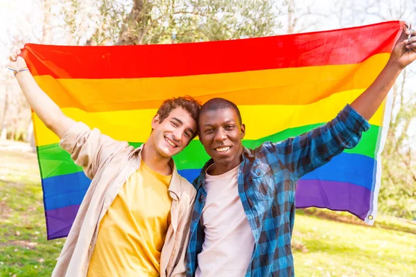 Portrét Multietnického Homosexuálního Páru Mužů Držícího Duhovou Vlajku Při Západu — Stock fotografie