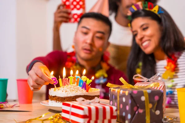家でソファの誕生日パーティーでお友達の多民族グループには ケーキやギフトがあり ろうそくに火をつけます — ストック写真