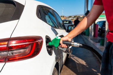 Silahlı bir adam benzin dolduruyor ya da beyaz bir arabada dizel yakıt. Ulaşım, enerji krizi, petrol krizi kavramı. Benzin istasyonunda bir fiyat krizinin ortasında depo dolu.