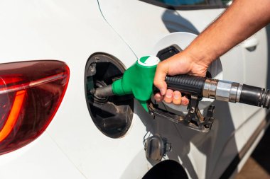Silahlı bir adam benzin dolduruyor ya da beyaz bir arabada dizel yakıt. Ulaşım, enerji krizi, petrol krizi kavramı. Benzin istasyonunda bir fiyat krizinin ortasında depo dolu.