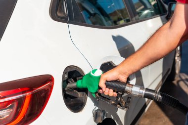 Benzin ya da dizel yakıtı beyaz bir araçla dolduran silahlı bir adamın eli. Ulaşım, enerji krizi, petrol krizi kavramı. Benzin istasyonunda bir fiyat krizinin ortasında depo dolu.