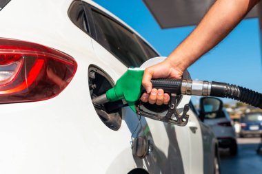 Benzin ya da dizel yakıtı beyaz bir araçla dolduran silahlı bir adamın eli. Ulaşım, enerji krizi, petrol krizi kavramı. Benzin istasyonunda bir fiyat krizinin ortasında depo dolu.