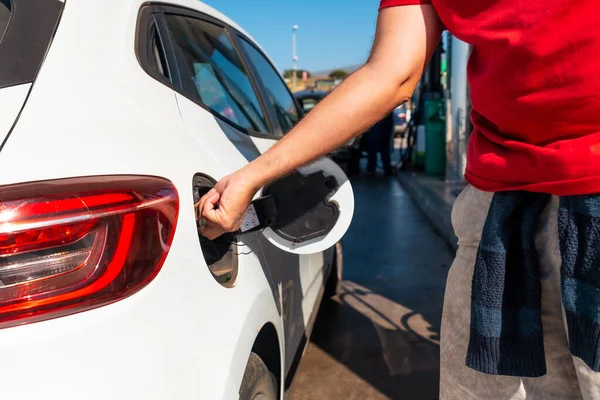 Man opening the car nozzle to refuel gasoline or diesel fuel in a white car. Concept of transportation, energy crisis, oil crisis. Full tank in the midst of a price crisis at the gas pump