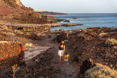 Anne ve oğlu gün batımında El Hierro, Kanarya Adaları 'ndaki Tacoron sahilinde bir patikada.