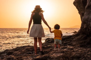 Silhouette of mother and son at sunset on the beach of Tacoron on El Hierro, Canary Islands, vacation concept, orange sunset clipart