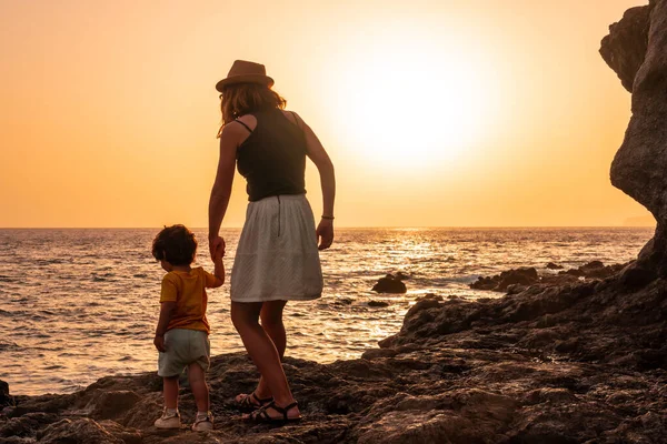 Silhouette of mother and son walking in the sunset on the beach of Tacoron on El Hierro, Canary Islands, vacation concept, orange sunset