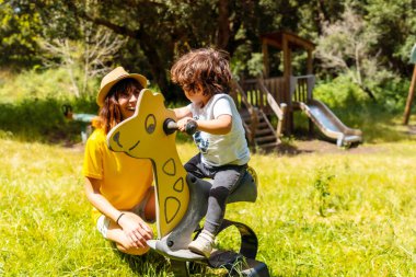 El Hierro, Kanarya Adaları 'ndaki La Llania parkında çocuk parkında eğlenen bir anne. Trek molası ve piknik