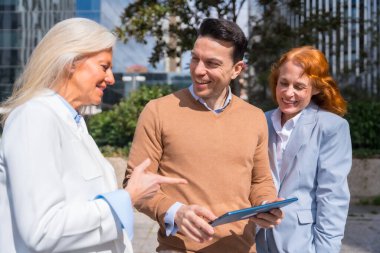 Grup yöneticileri, iş adamları ve iş kadınları. Gülmek ve tablete bakmak.