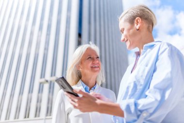 İşletme alanında yönetici kadınlar ve iş kadını tablete bakıp gülümseyen kadınlar.