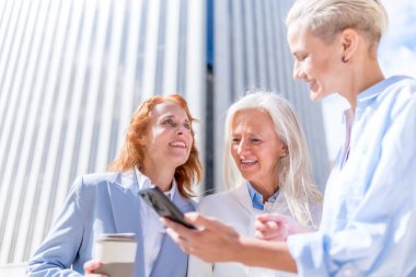 İşletme alanında yönetici kadınlar ve iş kadını, dışarıda dinlenirken tablete bakarak gülümseyen güçlü kadınlar.