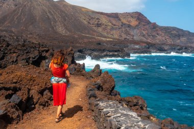 İspanya 'nın Kanarya Adaları' ndaki El Hierro adasındaki Tamaduste köyünde oğluyla volkanik yolda yürüyen bir anne.
