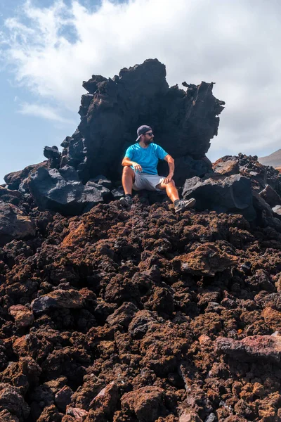 スペイン カナリア諸島エル ヒエロ島沿岸のタマドゥスト村の火山道の赤い石の上に座っている若い観光客 — ストック写真