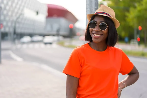 Νεαρή Μαύρη Γυναίκα Γυαλιά Ηλίου Και Καπέλο Πορτοκαλί Shirt Χαμογελαστή — Φωτογραφία Αρχείου